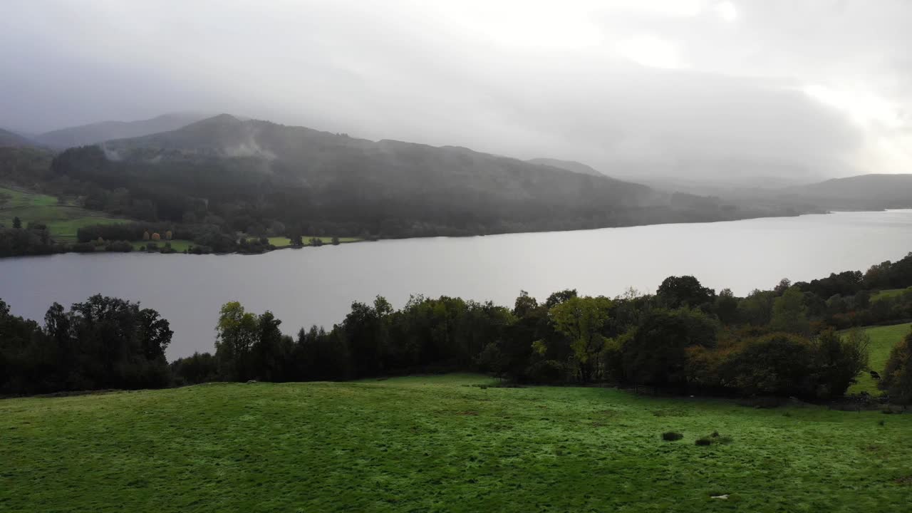 vista aérea de los árboles de la orilla del río sobre el valle verde con loch tummel en el fondo