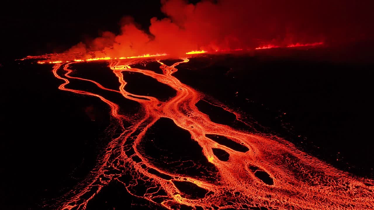 Fissure volcanic eruption exploding at night with glowing lava in Iceland, aerial