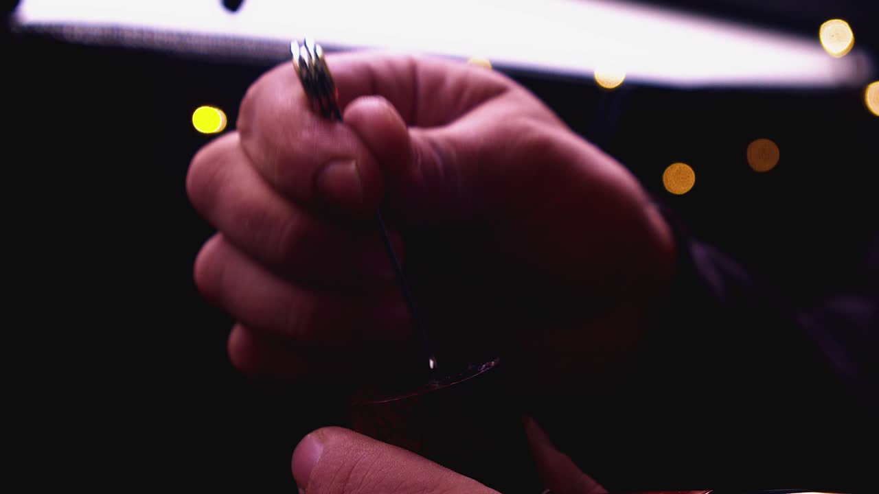 Backlit closeup: Man uses tamper to tamp tobacco in smoking pipe