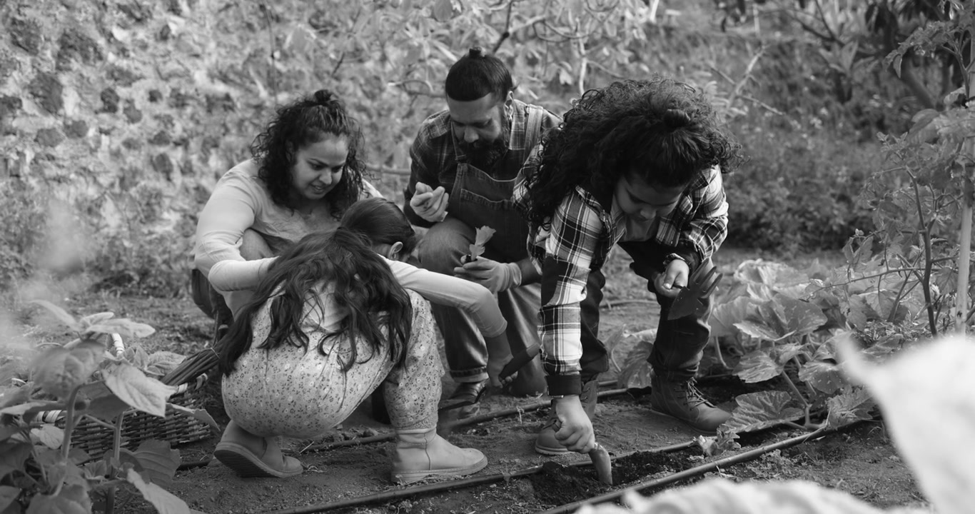 Famiglia felice che fa giardinaggio insieme in una fattoria rurale