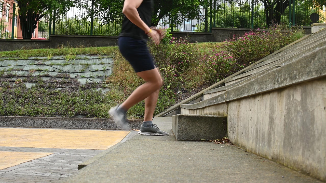屋外の階段を駆け上がりフィットネストレーニングをする若い男性