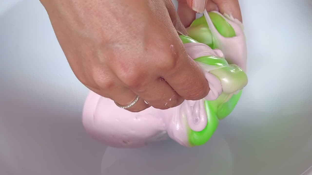 Donna che mescola slime verde e rosa su sfondo bianco