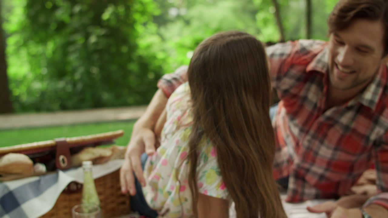 가족들이 숲에서 함께 놀고 있습니다. 즐거운 아이들과 부모들이 담요에 누워 있습니다.