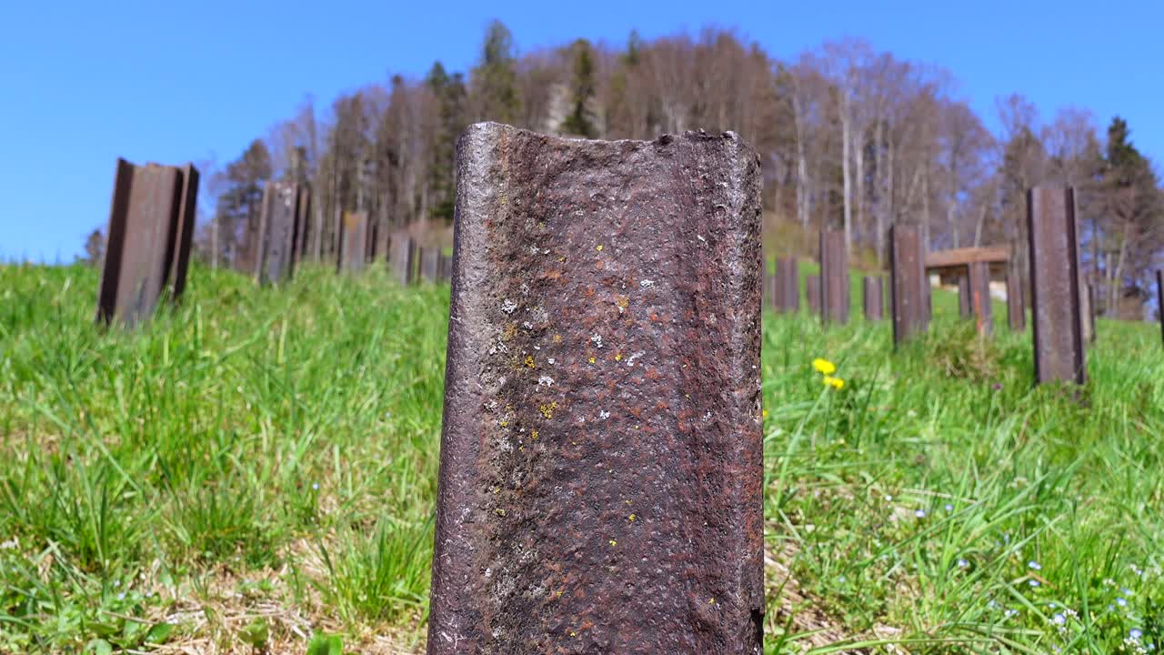 швейцарское противотанковое заграждение в сельском травянистом поле на холме при свете солнца