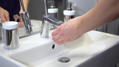 slow-motion of white male washing hands with tab water in sterile bathroom