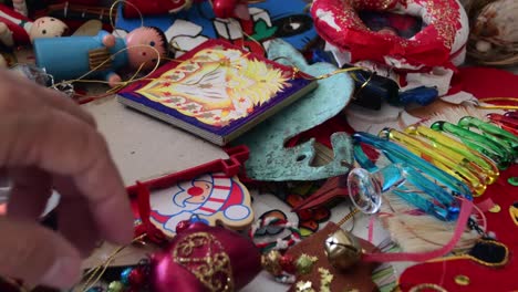 close-up of a pile of colorful christmas tree ornaments a hand reaches in to pick up one