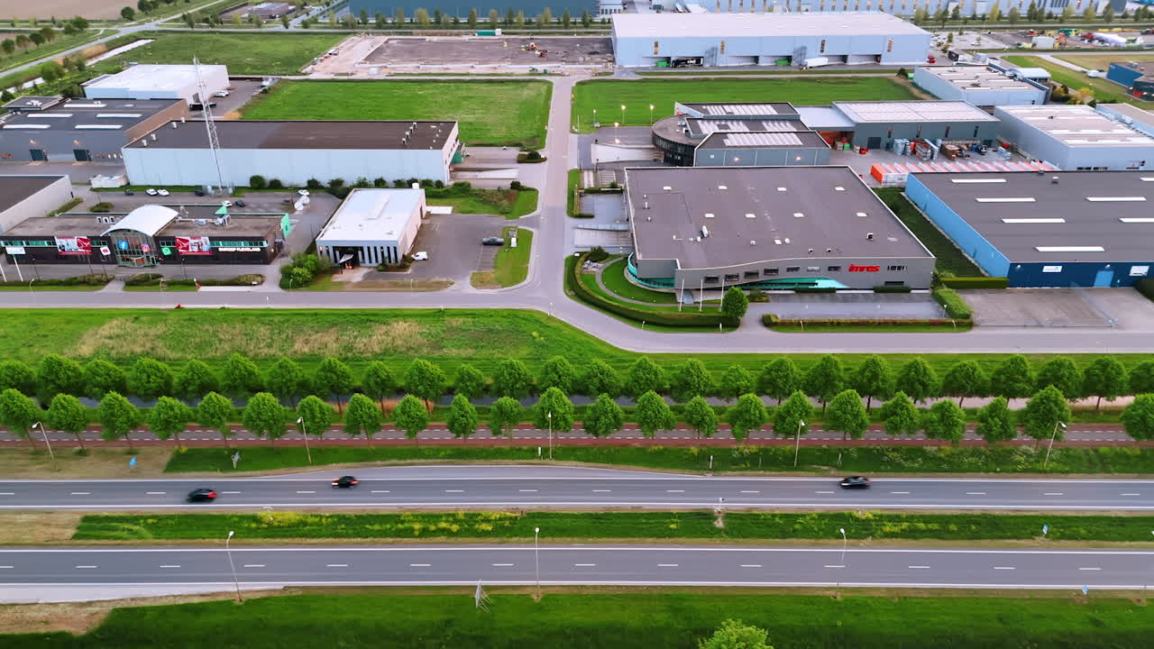 Large warehouses and malls along the highways in the countryside. Drone footage along the roads with cars passing by.