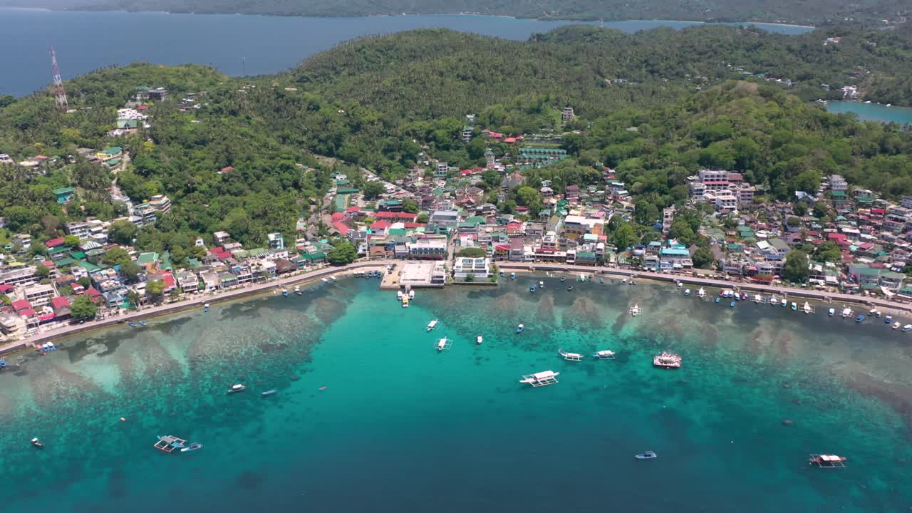 Stunning aerial video captures Puerto Galera and Sabang Bay with turquoise waters, boats, and diving schools, showcasing the tropical beauty of this famous Philippine destination