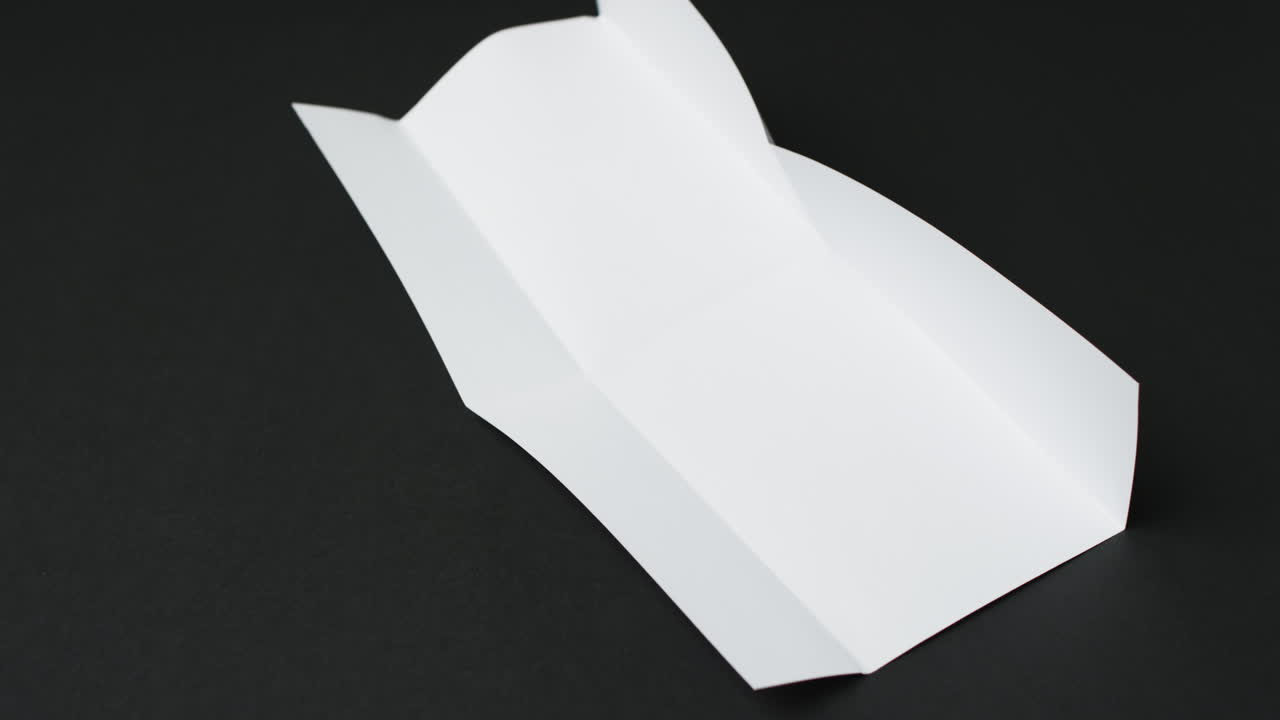 Video of piece of white paper with creases on black background