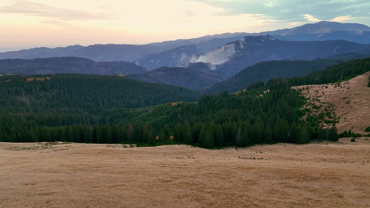 toma aérea que muestra el bosque en el valle y la cordillera en el fondo al atardecer - montañas dichiu en romana