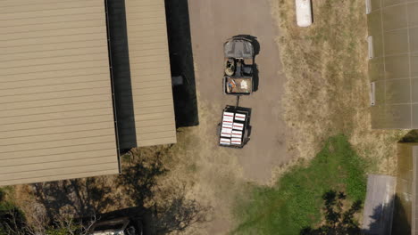 farmer's atv transporting trailer full of white boxes with fresh produce, aerial top down shot