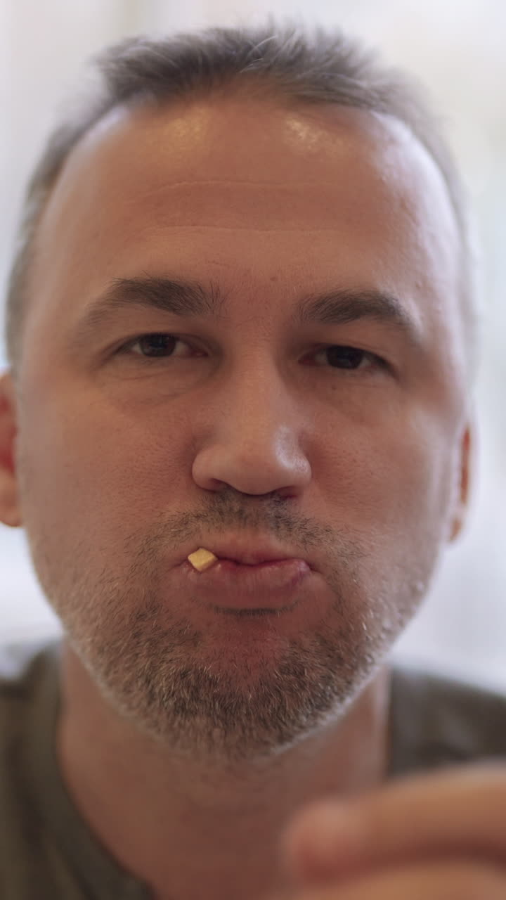 Young man portrait eating french fries in fast food restaurant. Harmful nutrition Vertical video