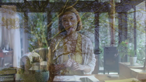 Working at desk, woman with animation of tree branches overlaying scene