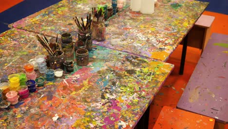 kids art table with messy paints and supplies