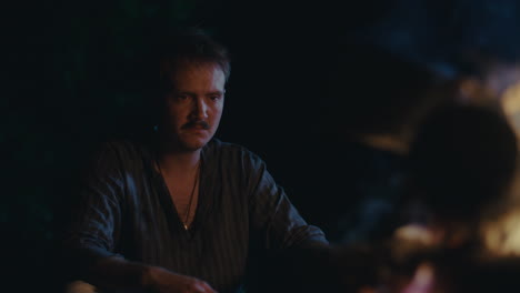 man with mustache by campfire at night