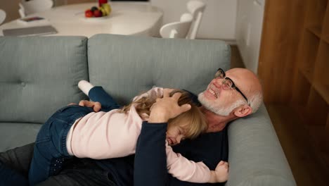 The-granddaughter-jump-on-her-grandfather-on-the-sofa-and-hug-him