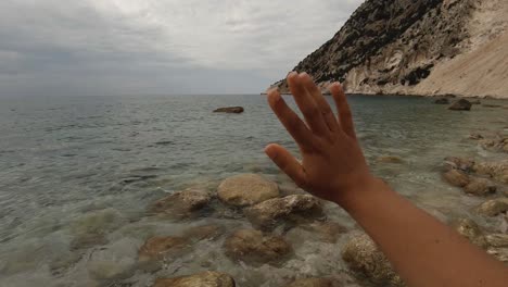 la mano de una niña despidiéndose en el mar