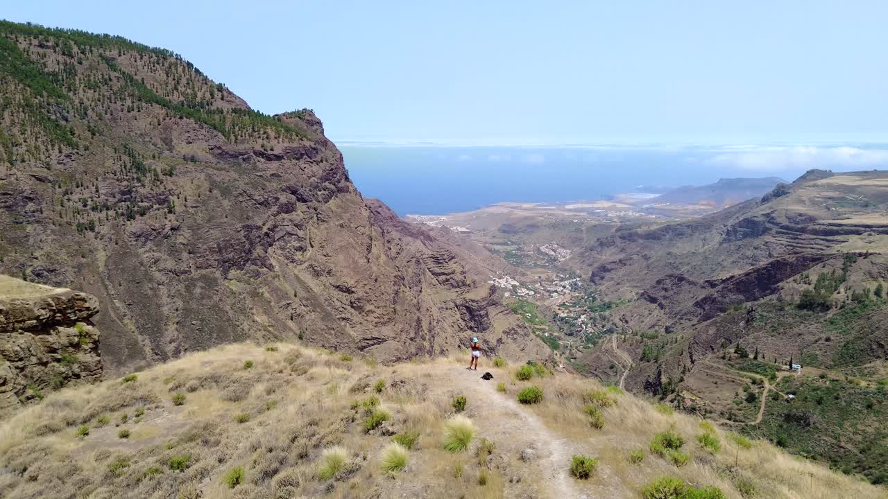 chica turista en la cima de la montaña extendida con los brazos abiertos drone vista aérea del valle y el paisaje en gran canaria