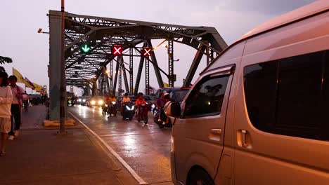 vehículos y peatones cruzando el puente al anochecer