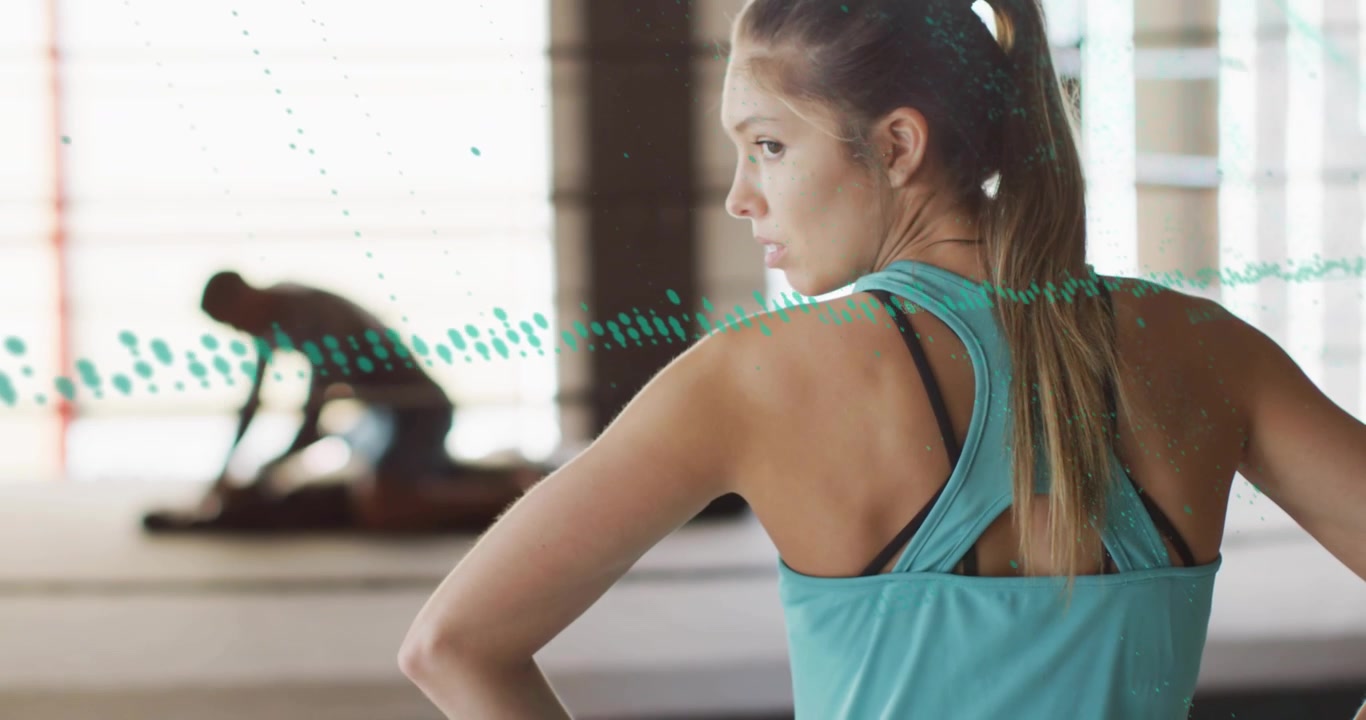 Woman turquoise tank red wraps, pan showing teal dots moving, man adjusting mat, prepping gym