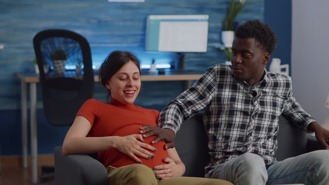 Married interracial couple expecting child sitting at home
