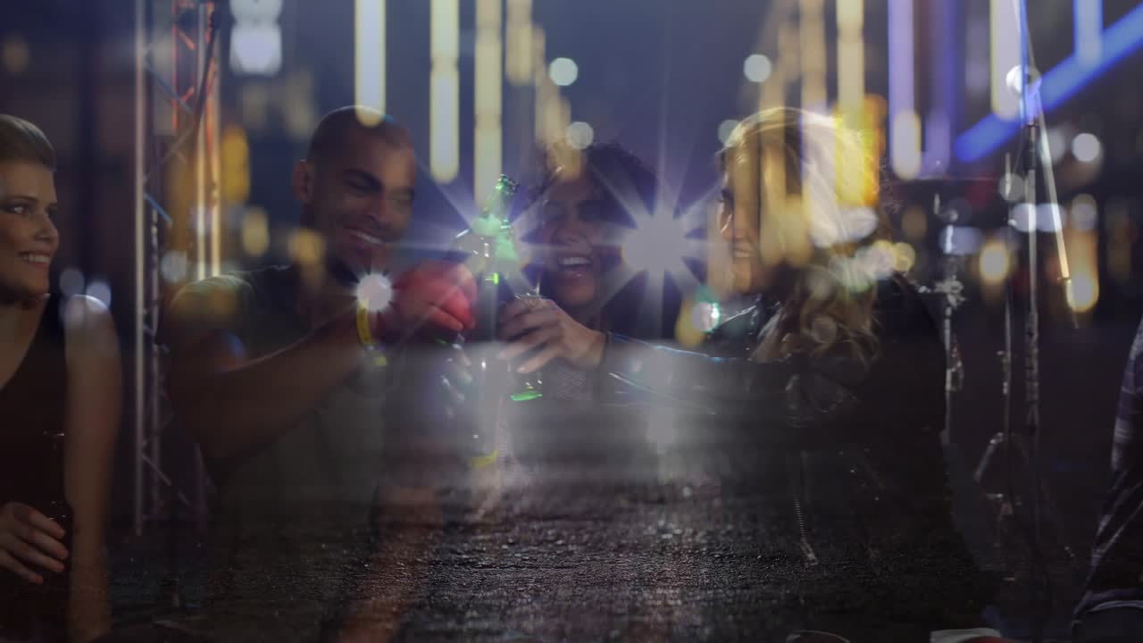 Three friends chatting, lifting beers at hospitality bar, neon headlight overlay boosting nightlife
