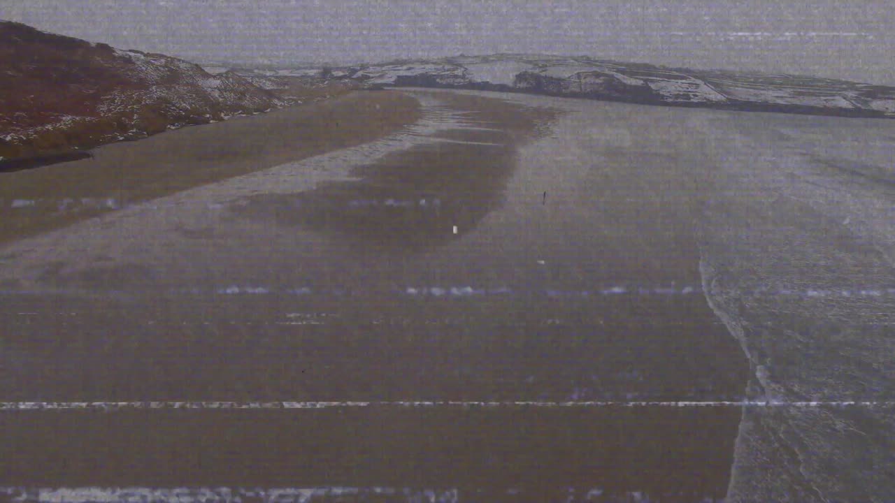 Wind-driven waves rolling onto shore, cresting and receding, revealing pools with static flickering