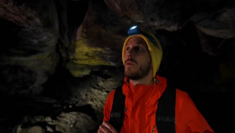 male hiker exploring a dark cave 4k