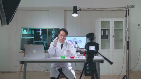 asian scientist man taking solution from test tube with micropipette putting in petri dish and talking to camera with professional lighting