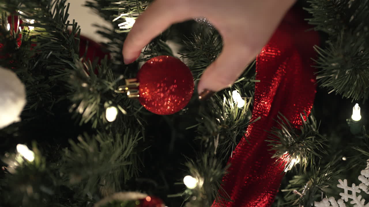primer plano de la mano poniendo adorno en el árbol de navidad - video vertical