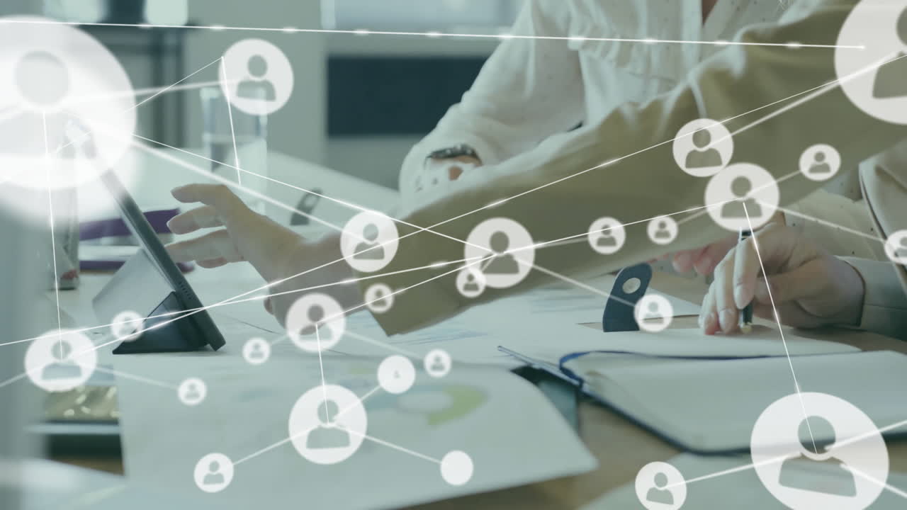 animación de iconos conectados sobre compañeras de trabajo caucásicas analizando informes en tableta digital