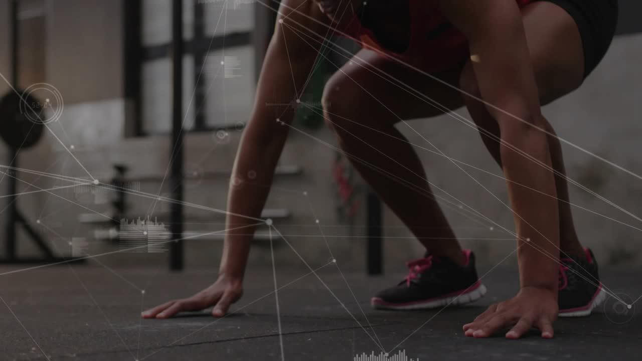 Performing mid-adult woman wearing red top moving push-up into tuck jump at gym with HUD overlay