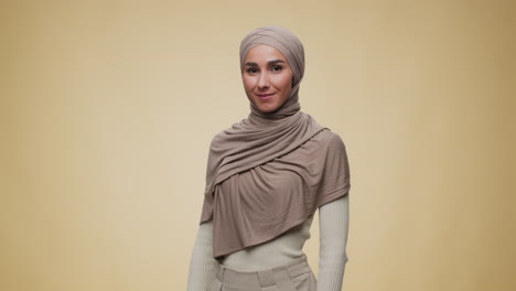 smiling woman in hijab making heart shape with hands