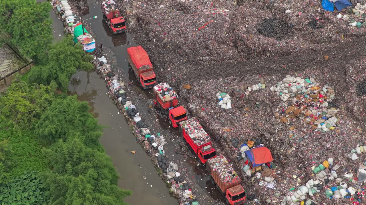 Vista aerea di camion della spazzatura in un'enorme discarica a Jakarta.
