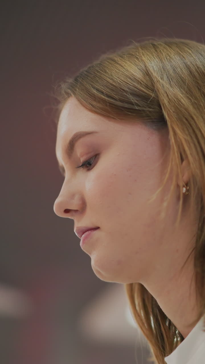 perfil lateral de una mujer joven que se concentra en el trabajo en un entorno interior moderno con iluminación de fondo abstracta borrosa, que transmite enfoque, productividad y atmósfera profesional