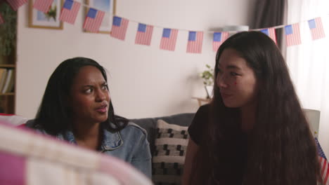 Friends-At-Home-Celebrating-With-Party-For-American-Independence-Day-4th-July-Talking-And-Eating-Snacks