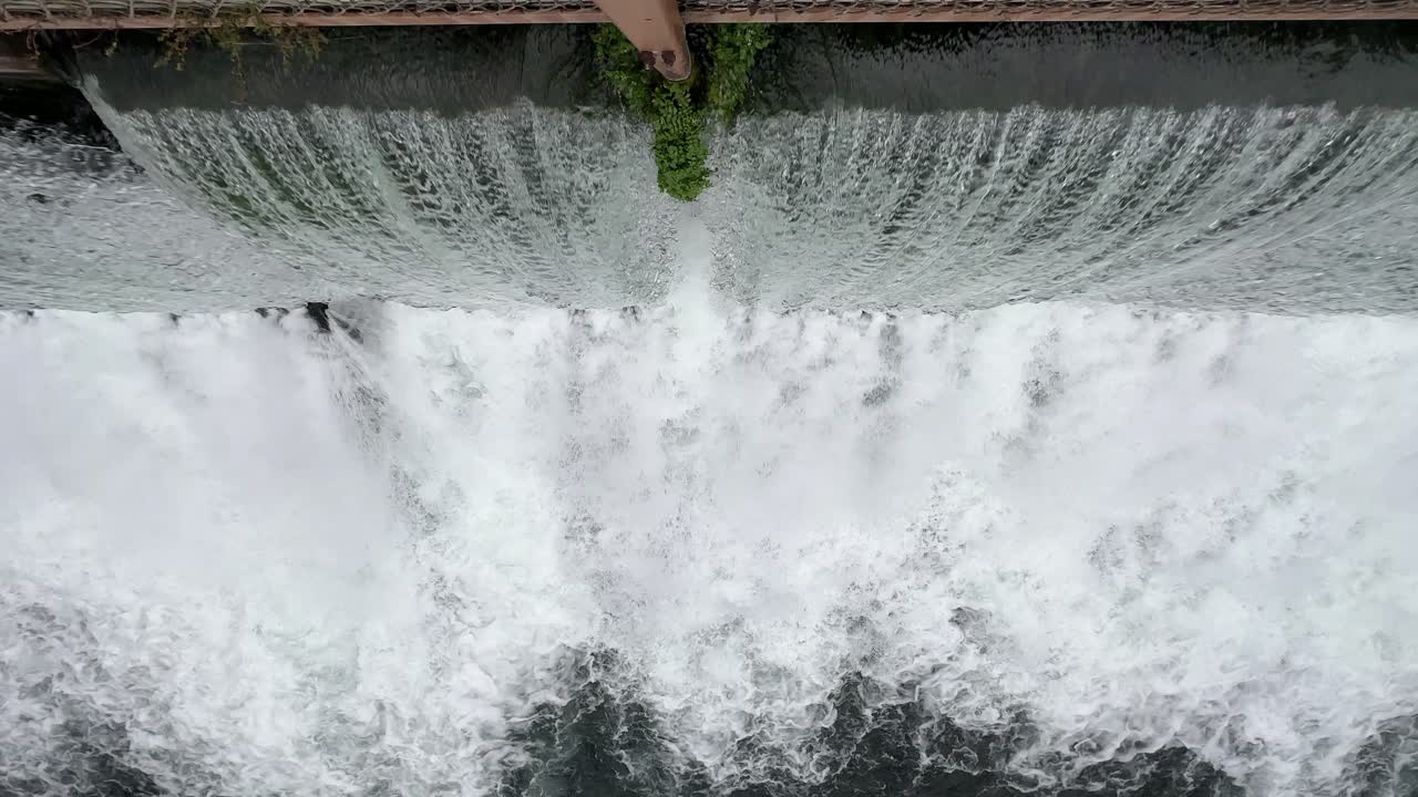 rushing water thru a dam looking straight down from drone angle 4k 30fps