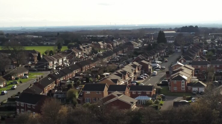 Rural British townhouse neighbourhood homes with green space aerial view across to Snowdonia mountain skyline, Orbiting right