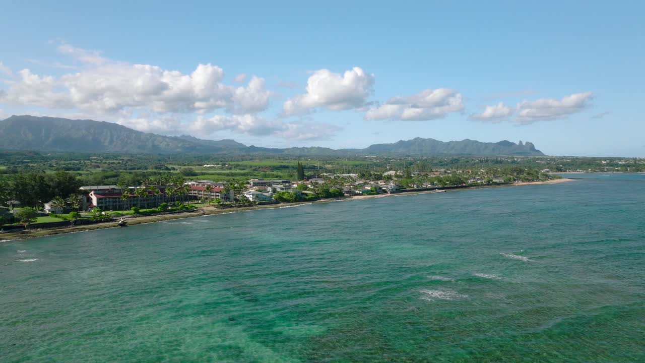 Onde oceaniche turchesi aeree che scorrono dolcemente verso la costa tropicale di Kauai.