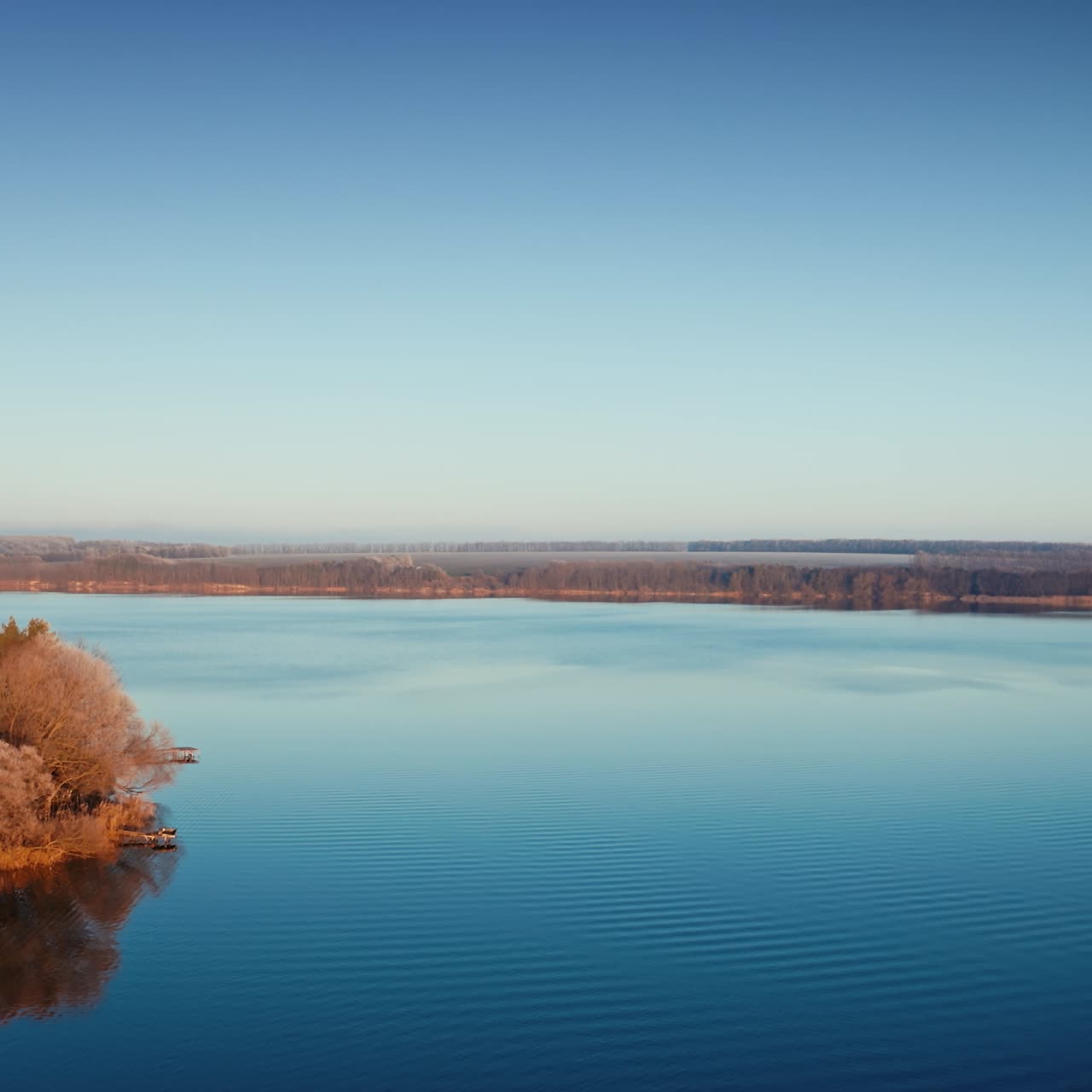 Calm river at sunrise. Winter landscape over the river. Slight mist on trees near the river. Amazing nature in the morning. Aerial view.