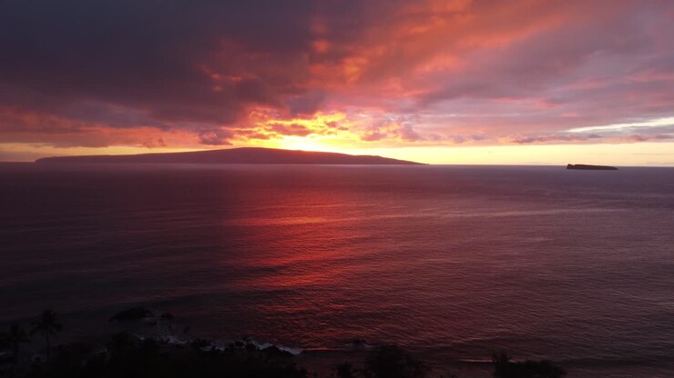 Stunning aerial view of Molokini Crater and the sacred island of Kaho'olawe in the distance during amazing red sunset in Maui, Hawai'i