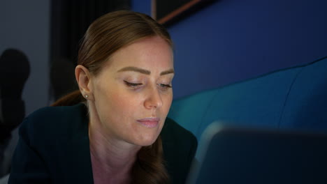 Close-up-of-an-attractive-girl-lying-on-a-sofa-at-night-using-a-laptop