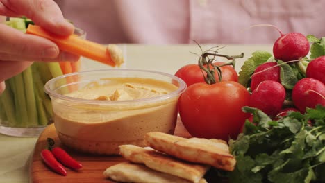 person eating hummus with vegetables