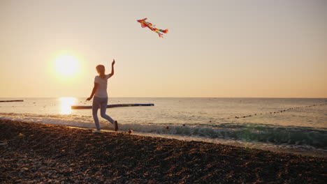 woman with kite runs along the beach steadicam shot