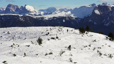 caminante solitario caminando hacia los picos masivos de las montañas nevadas de los dolomitas en un paraíso invernal de rittner horn cerca de bolzano, italia