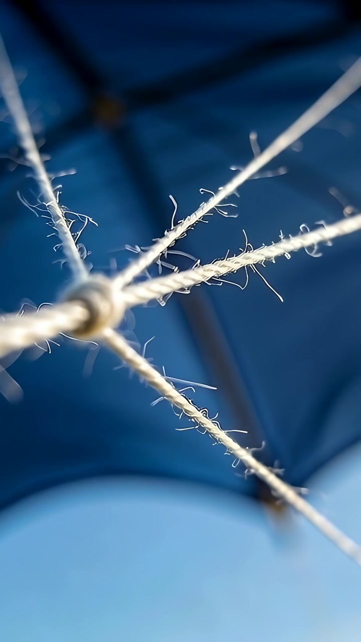 Video verticale: Nodo di spago che si sposta sotto una tettoia, la brezza e lo spostamento della telecamera fanno brillare le fibre sfilacciate.