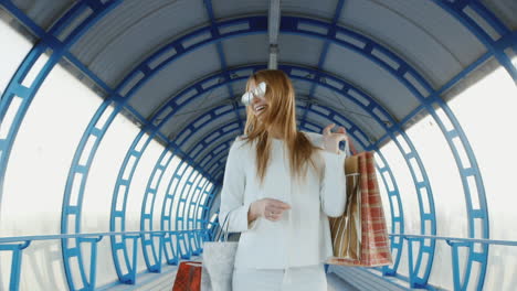 steadicam disparó a una joven elegante con bolsas de compras hablando sobre una transición de vidrio moderna o un túnel