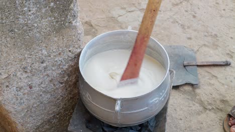 white banku mixture stirred in a pot on a charcoal stove, national dish of ghana