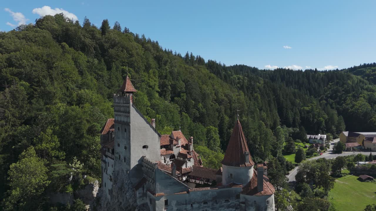 Drone che vola all'indietro, rivelando gradualmente il Castello di Bran con pittoresche colline sullo sfondo