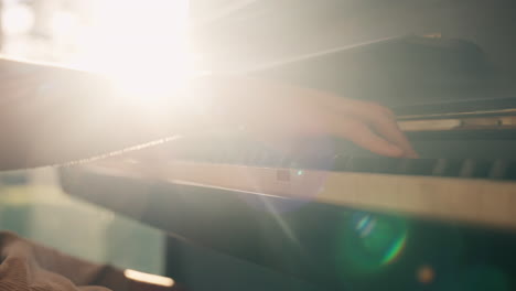 close up of hands playing grand piano, back lit with golden sunlight lens flairs